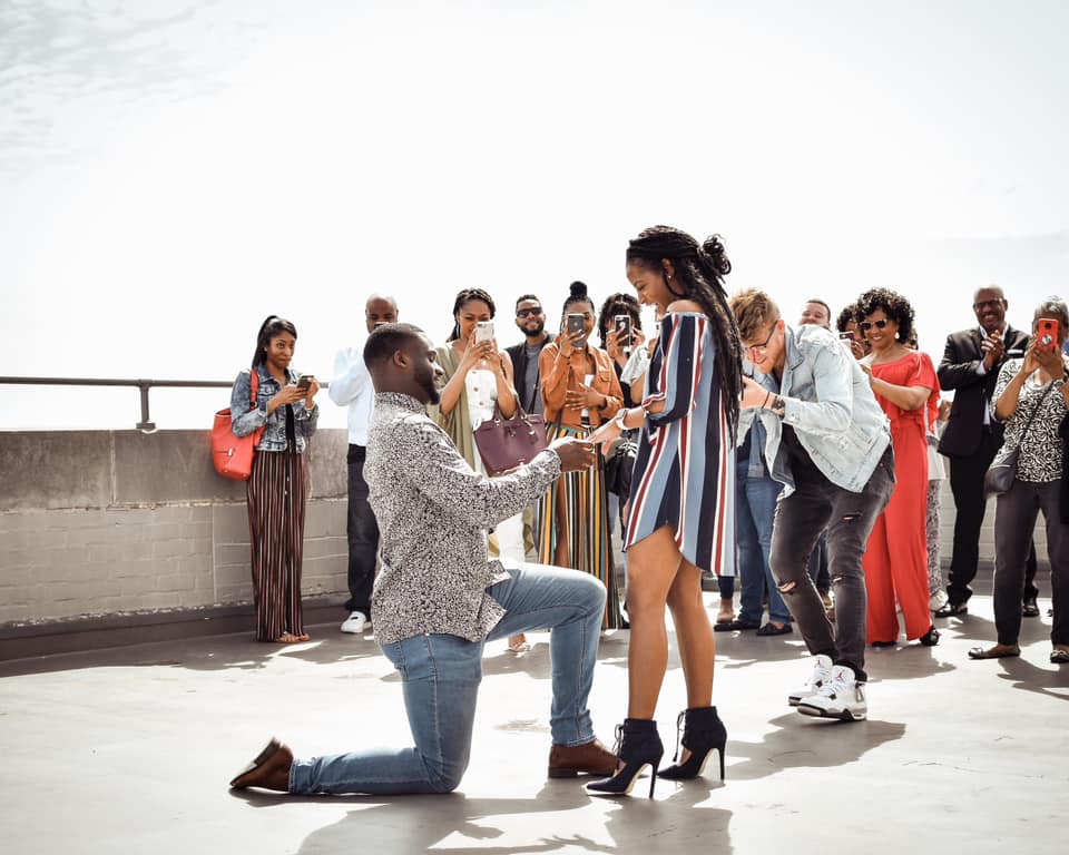 Proposal with friends and family in the background
