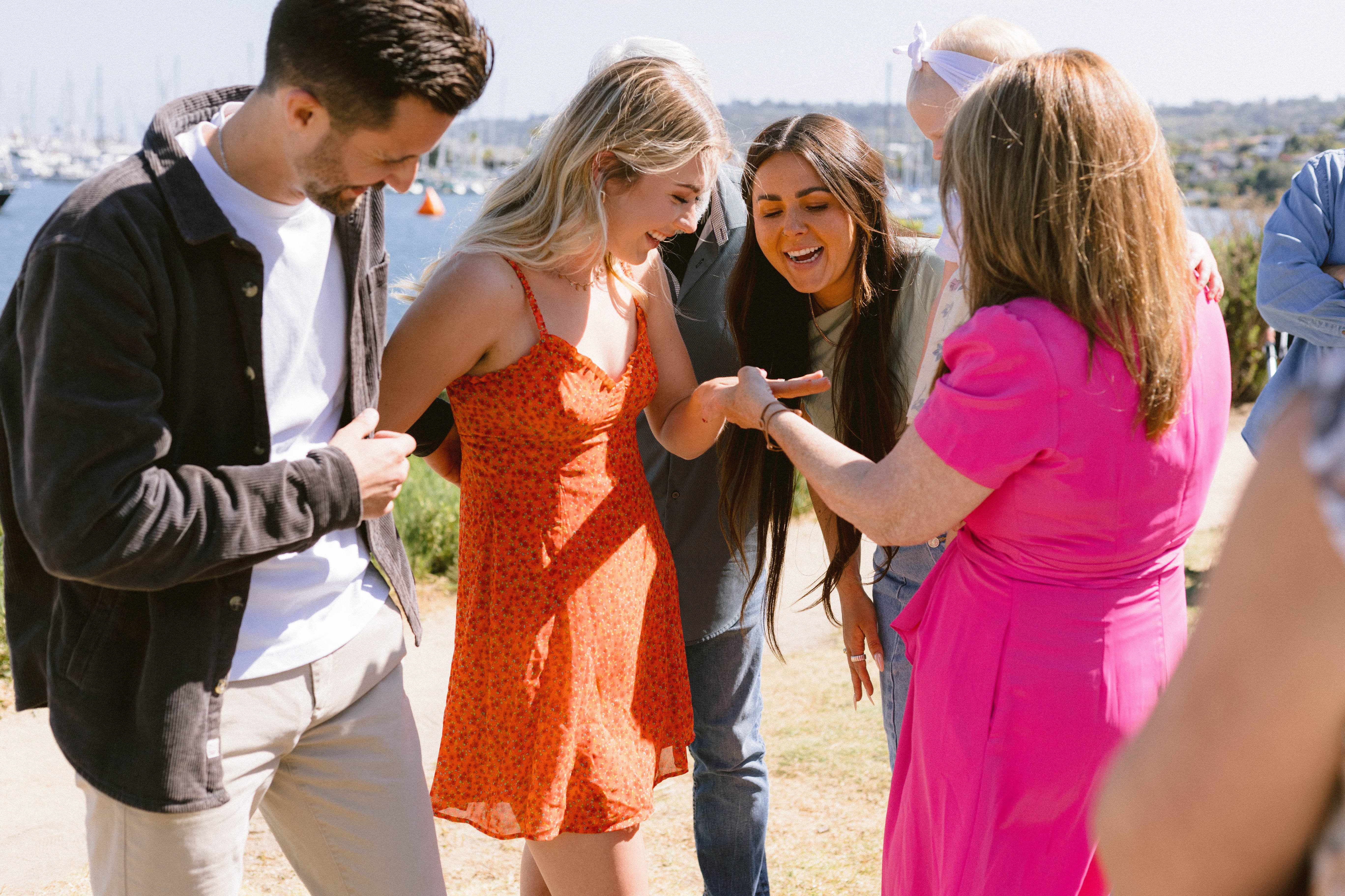 Cheerful friends looking at the ring of a newly engaged couple
