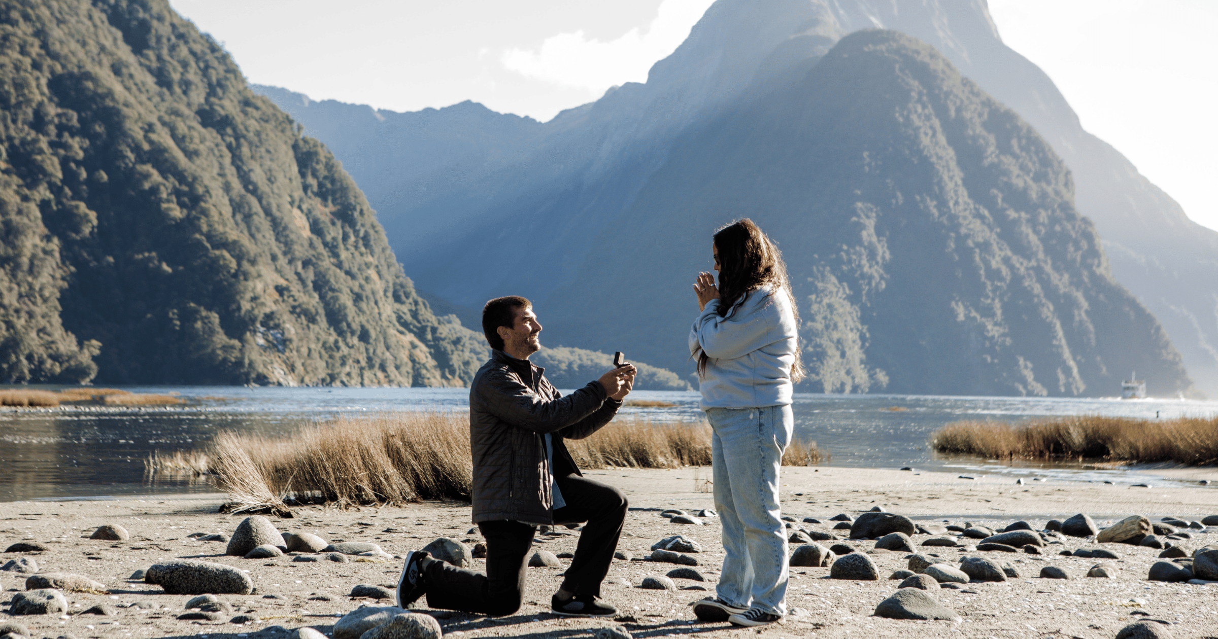 Couple Getting Engaged on a Rocky Beach with Mountains