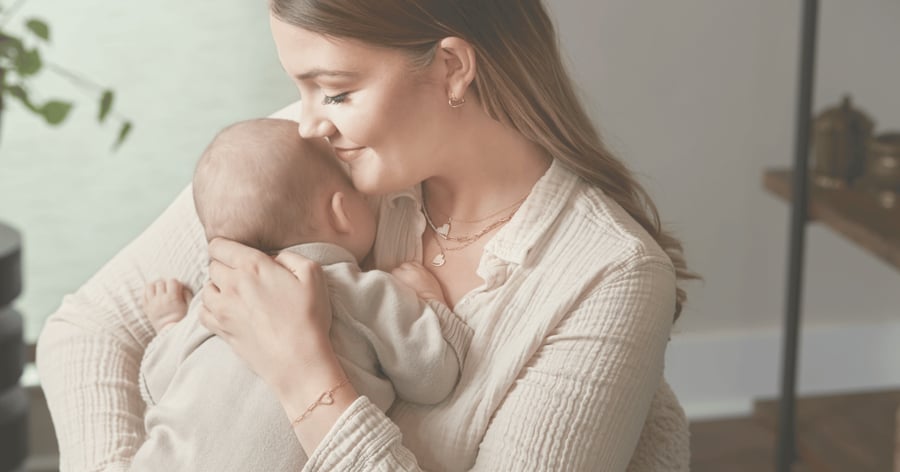 Mother_holding_new_baby_showing_push_present_of_yellow_gold_heart_jewelry