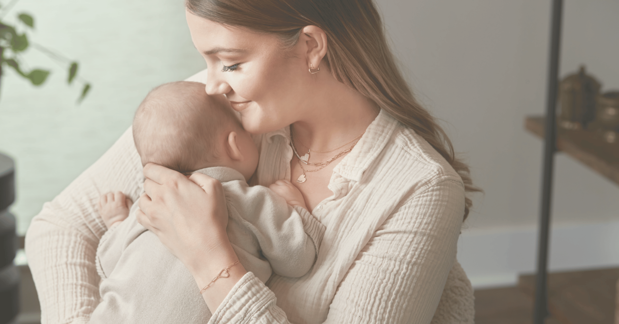 Mother_holding_new_baby_showing_push_present_of_yellow_gold_heart_jewelry