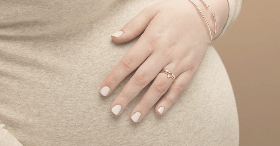 Pregnant_woman_holding_belly_showing_push_present_of_yellow_and_rose_gold_jewelry