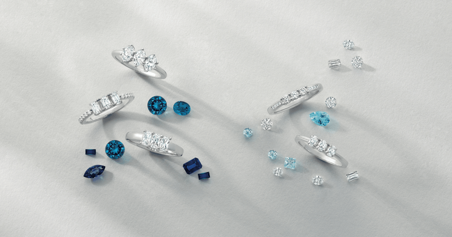 Various White Gold (or Platinum) Diamond Rings with Blue Gemstones in Background