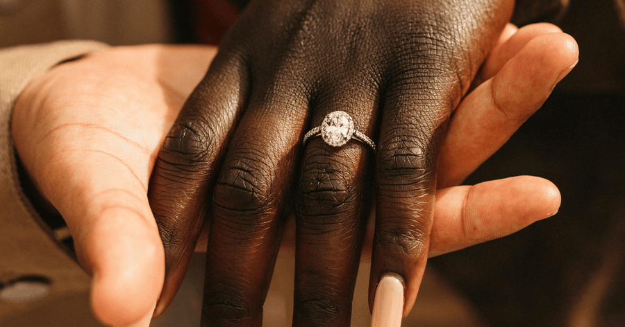 White Gold (or Platinum) Diamond Halo Accented Engagement Ring set with an Oval Cut Diamond shown on Left Hand Ring Finger