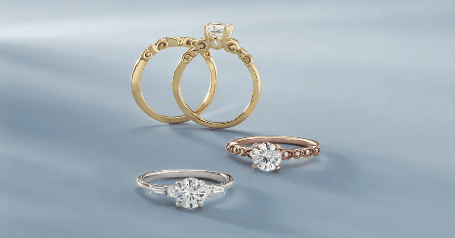 Yellow Gold Engagement Ring with Accent Stones and Detailing set with a Round Cut Diamond and Matching Wedding Band; White Gold (or Platinum) Engagement Ring with Accent Stones set with a Round Cut Diamond; Rose Gold Engagement Ring with