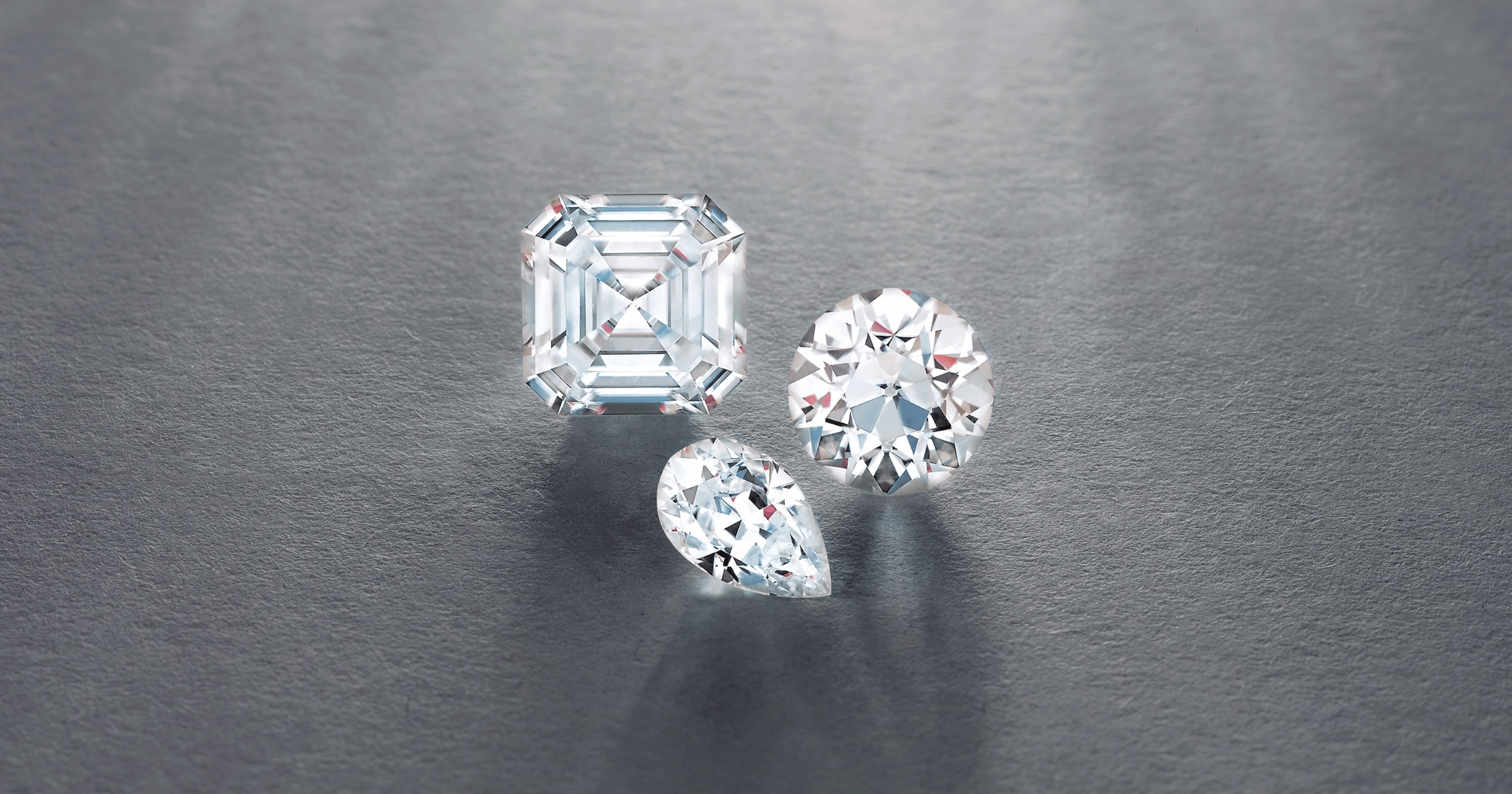 Loose Round Cushion and Pear Cut Diamonds on Reflective Grey Background