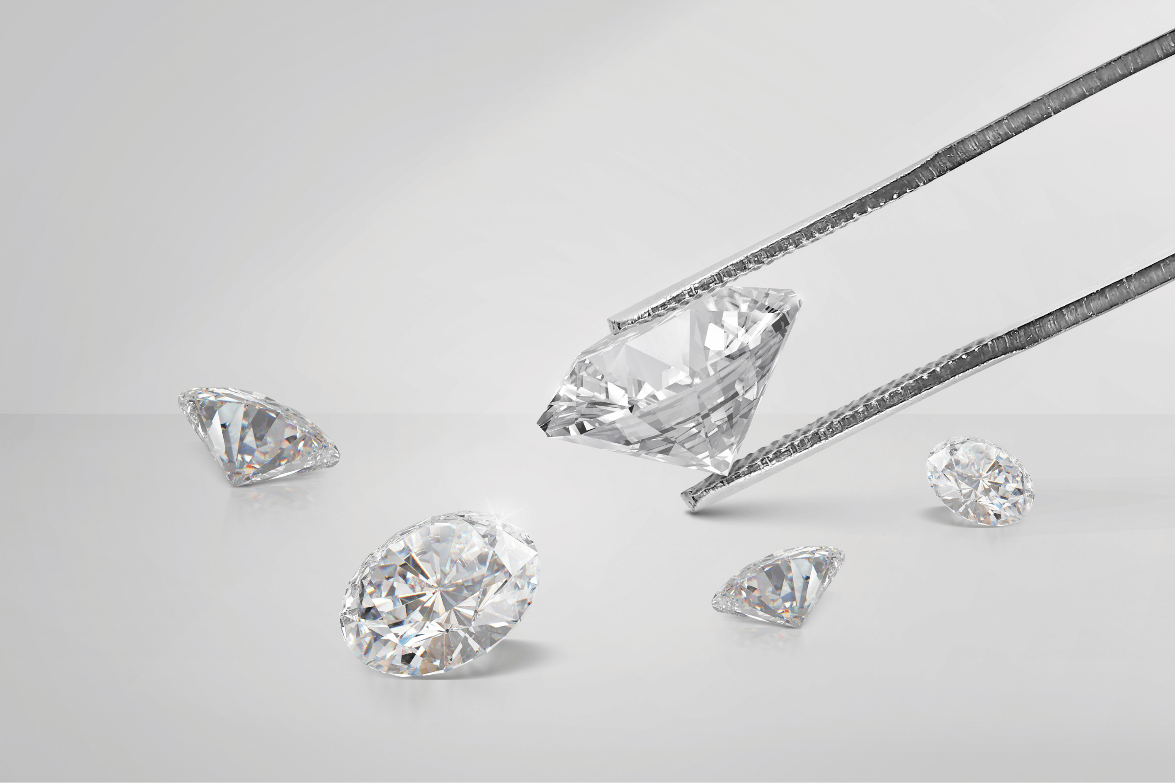 Various Shaped Diamonds Inspected with Tweezers on Grey Background