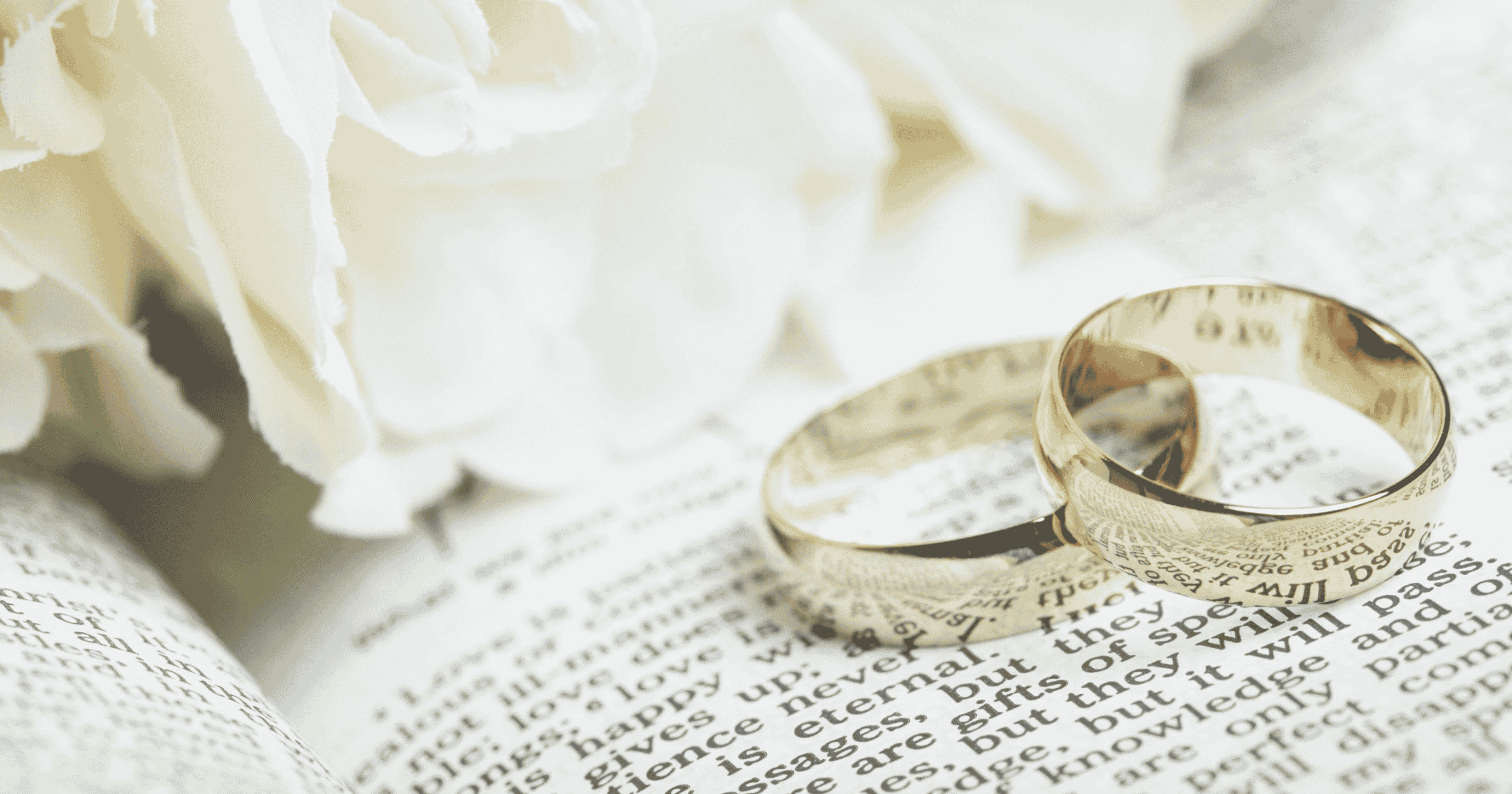 Gold Wedding Bands on Bible with White Flowers