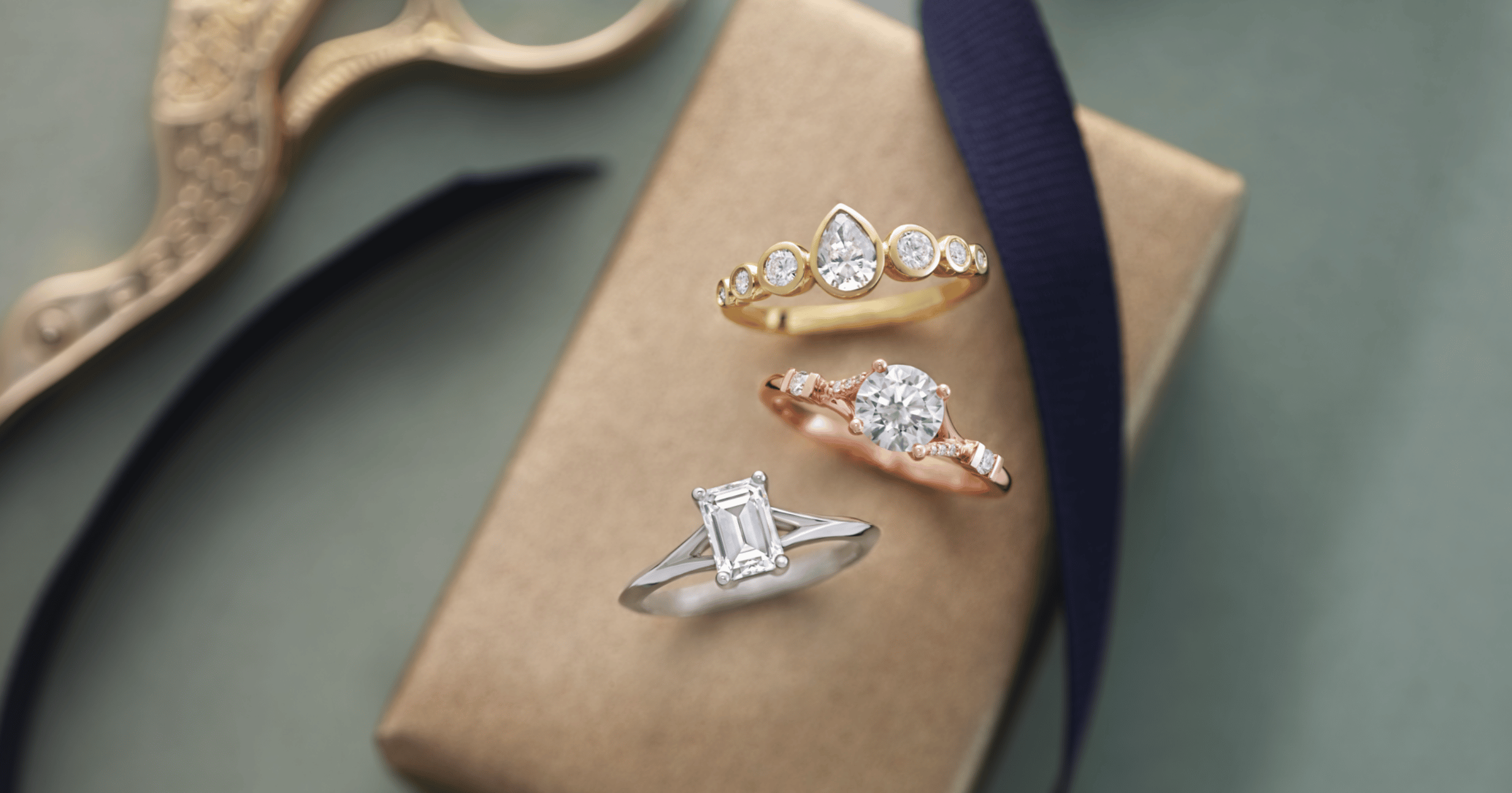 Yellow Gold Accented Engagement Ring set with a Pear Cut Diamond; Rose Gold Accented Engagement Ring set with a Round Cut Diamond; White Gold (or Platinum) Split Shank Engagement Ring set with an Emerald Cut Diamond