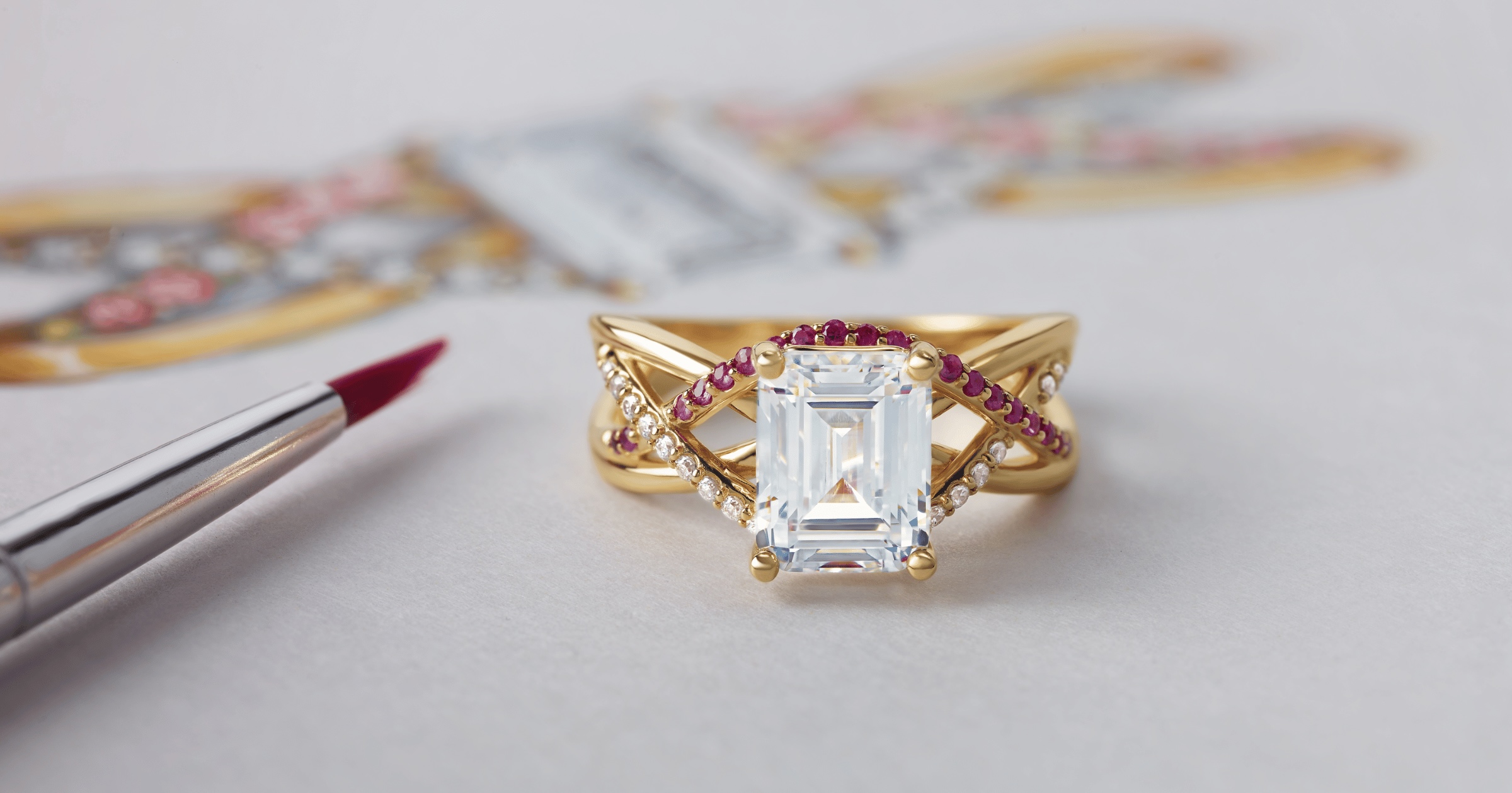 Intricate Emerald Engagement Ring with Accenting Diamonds and Rubies with Sketch of Ring in Background