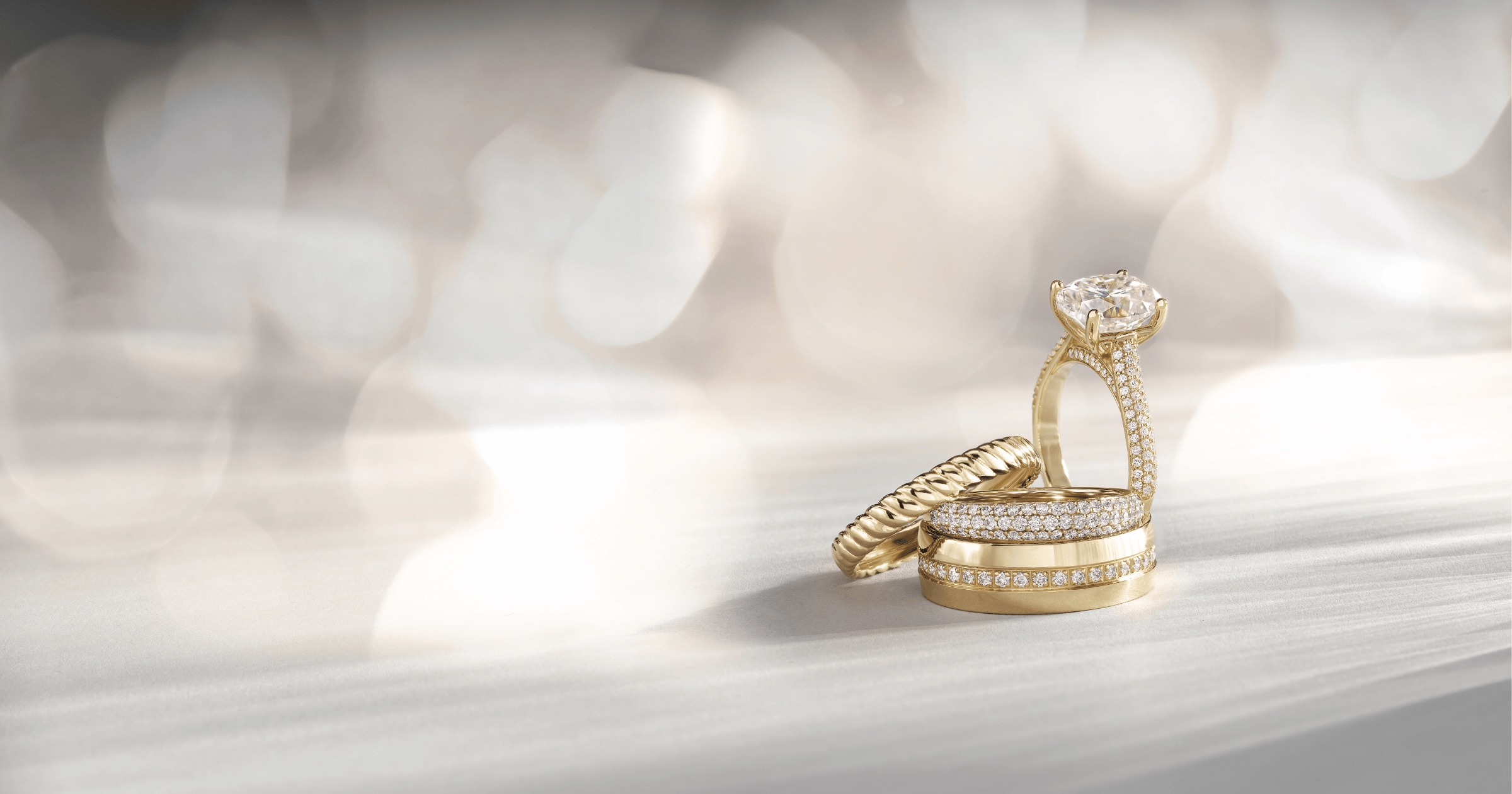 Yellow Gold Oval Diamond Engagement Ring with Accenting Diamonds Next to Complimenting Yellow Gold Diamond Accented Wedding Bands
